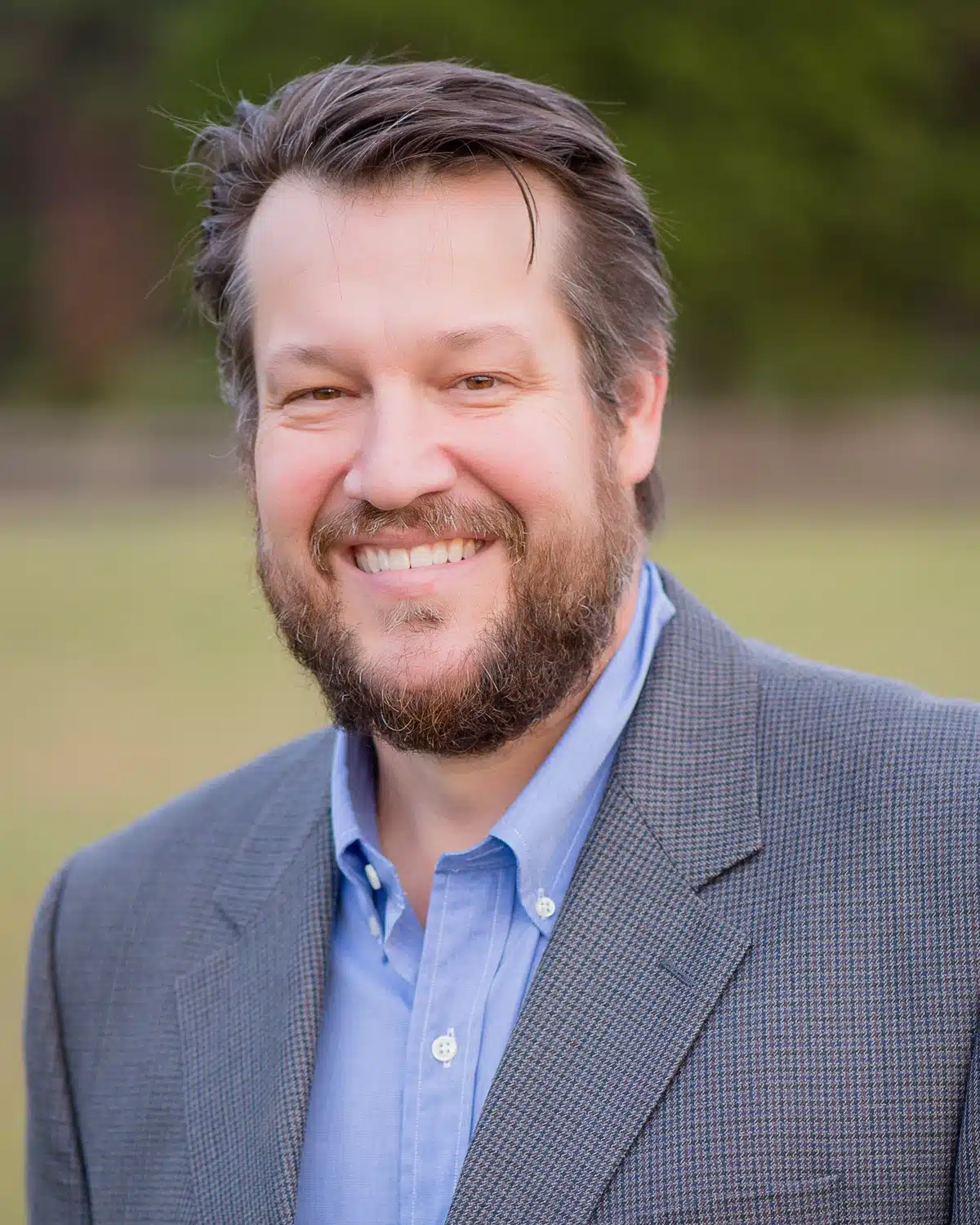 a man wearing a suit and tie smiling at the camera